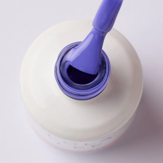 Open bottle of pastel purple gel nail polish with brush on white background