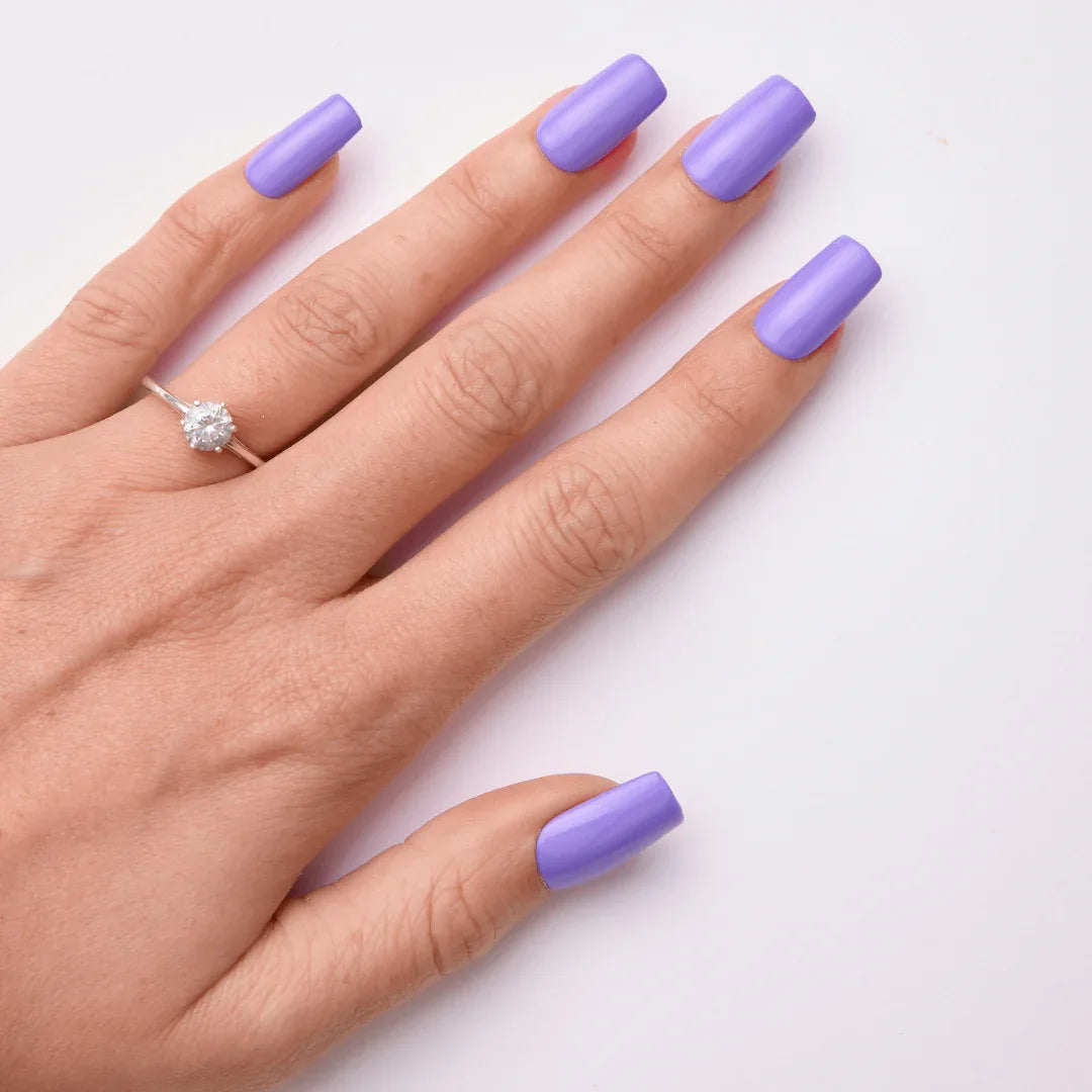 Hand with long square-shaped nails painted lavender purple, showcasing gel nail polish