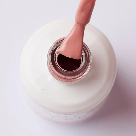 Close-up of pink gel nail polish brush over open bottle, professional nail product